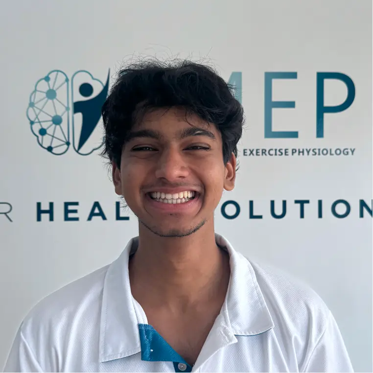 A young man with dark hair smiles broadly, standing in front of a wall with the words HEP and HEALTH SOLUTIONS partially visible and a logo featuring a stylised human figure and network design.
