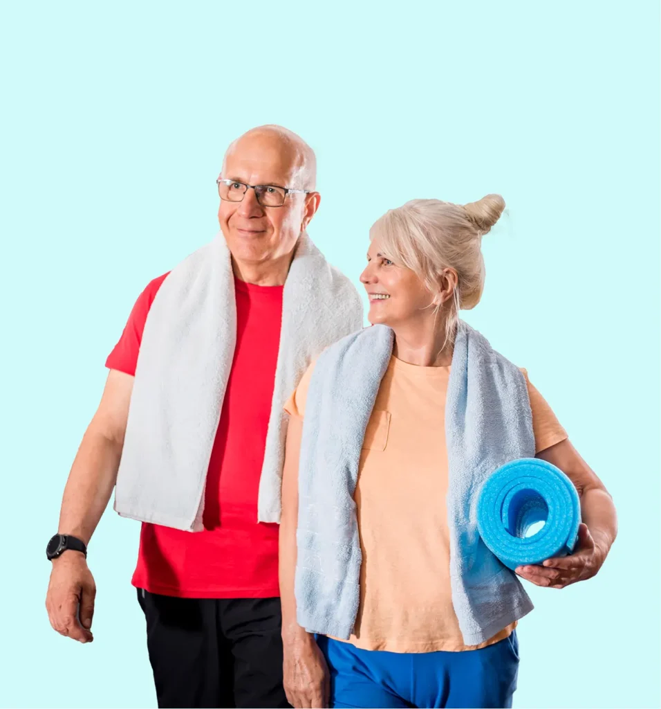 Two smiling older adults in workout clothes with towels around their necks; the woman holds a blue exercise mat. They appear ready for fitness activities against a light blue background.